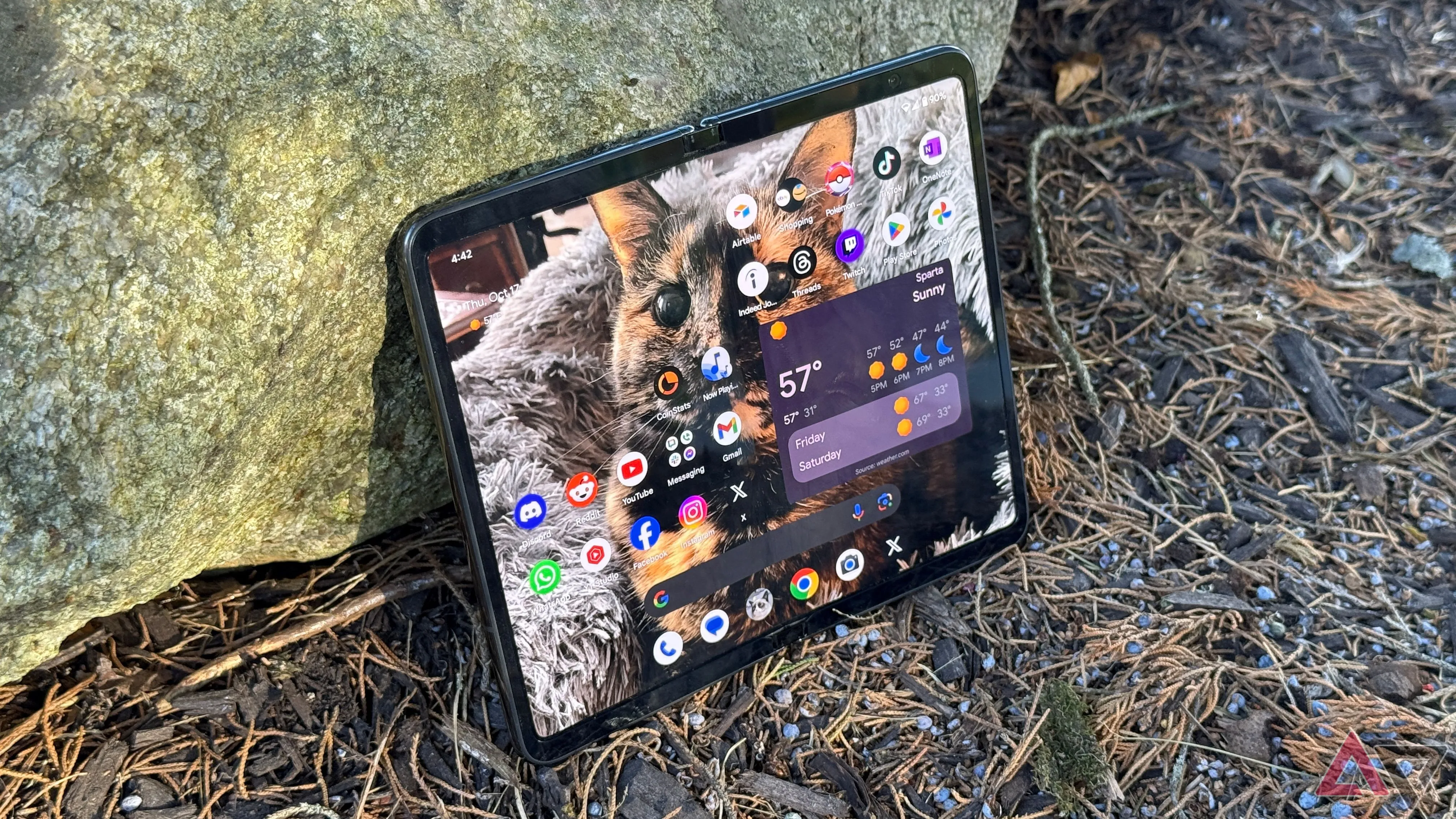 Điện thoại Google Pixel Fold màu Obsidian dựa vào đá ngoài trời, biểu thị độ bền và thời lượng pin cải thiện