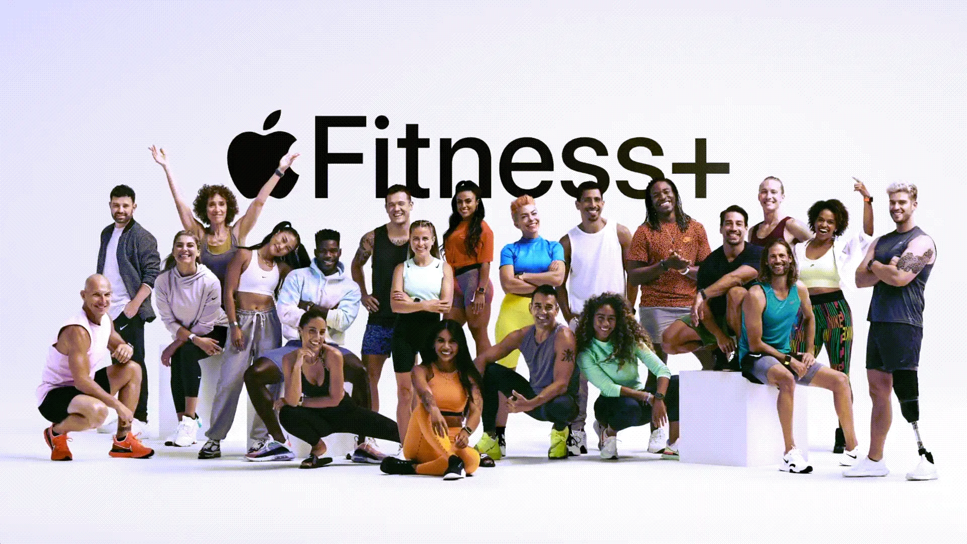Hình ảnh một nhóm lớn huấn luyện viên cá nhân đứng trước logo Apple Fitness+.