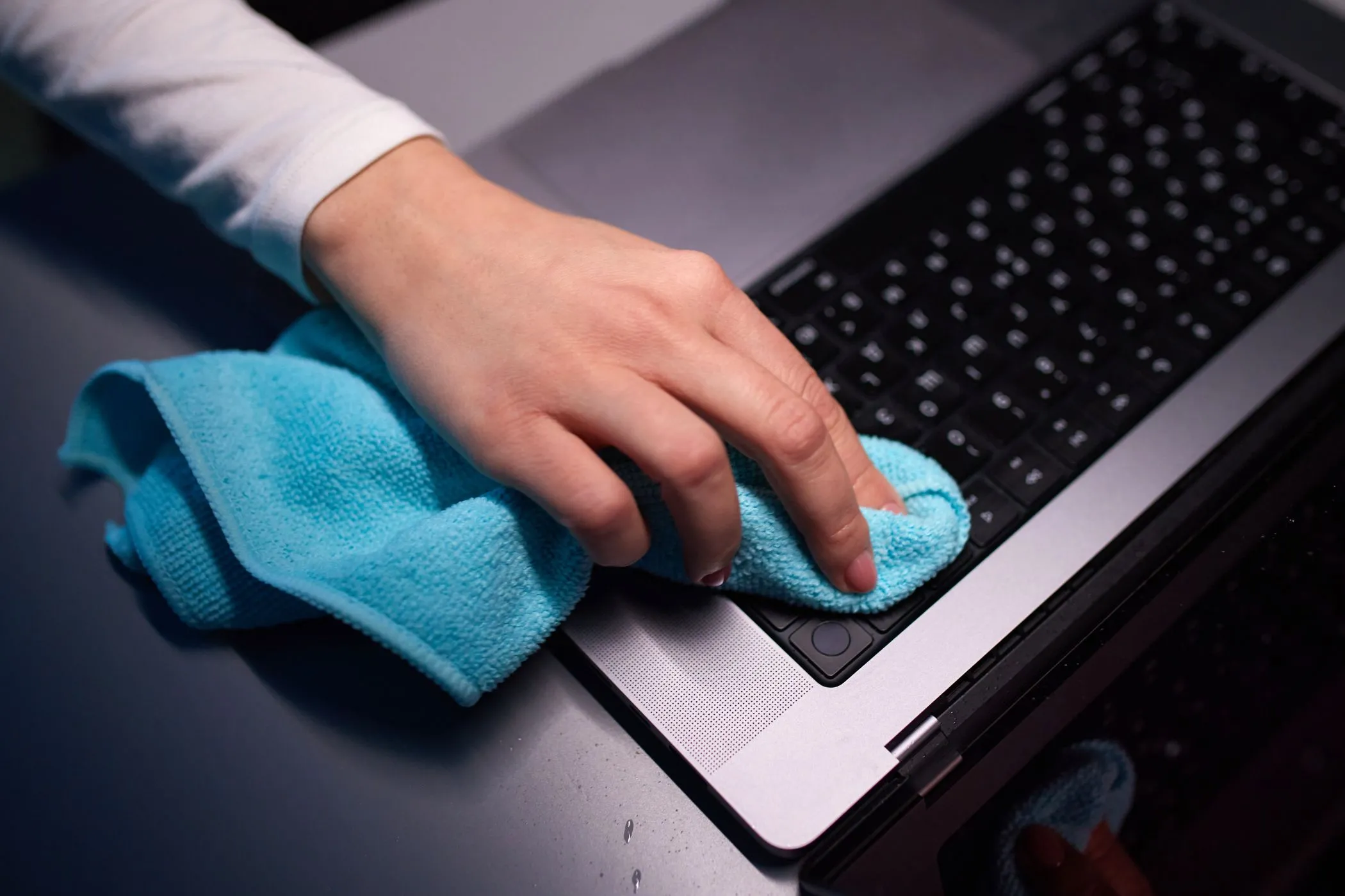 Một người dùng khăn microfiber màu xanh lá cây để vệ sinh màn hình MacBook Pro, nhấn mạnh tầm quan trọng của việc làm sạch