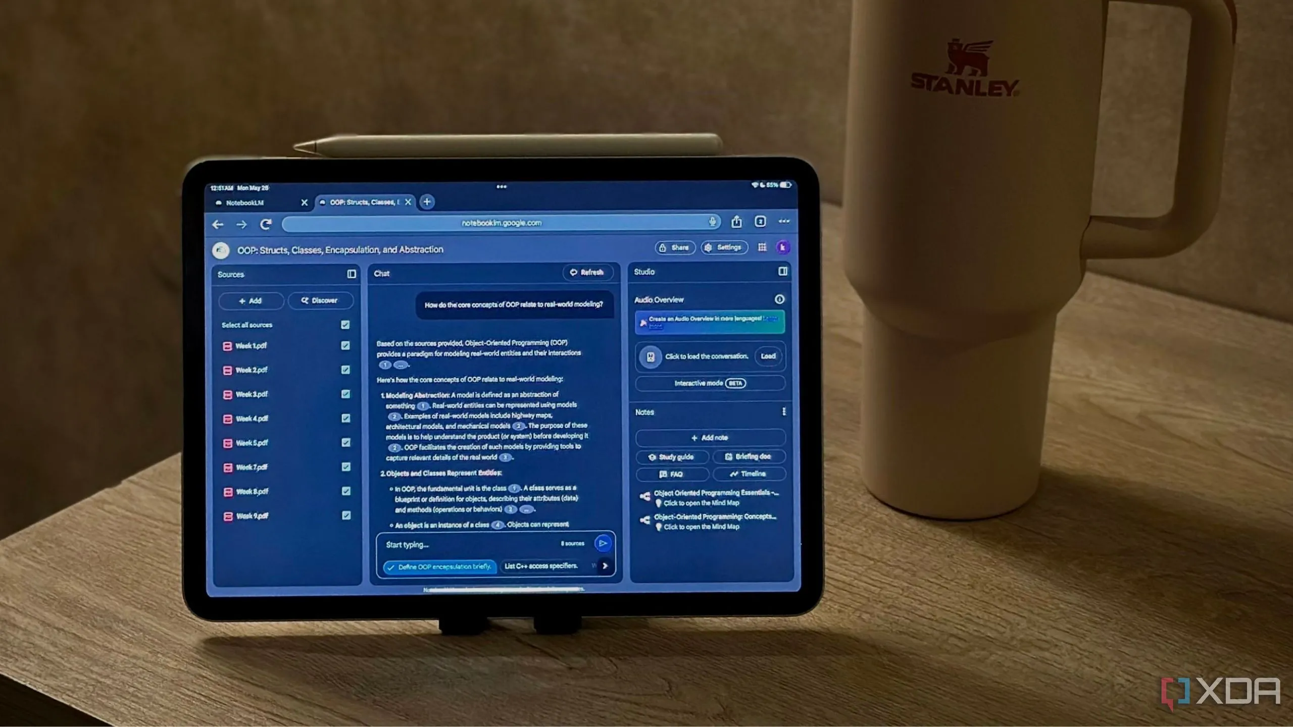 Giao diện NotebookLM hiển thị một Notebook OOP bên cạnh chiếc cốc Stanley màu hồng