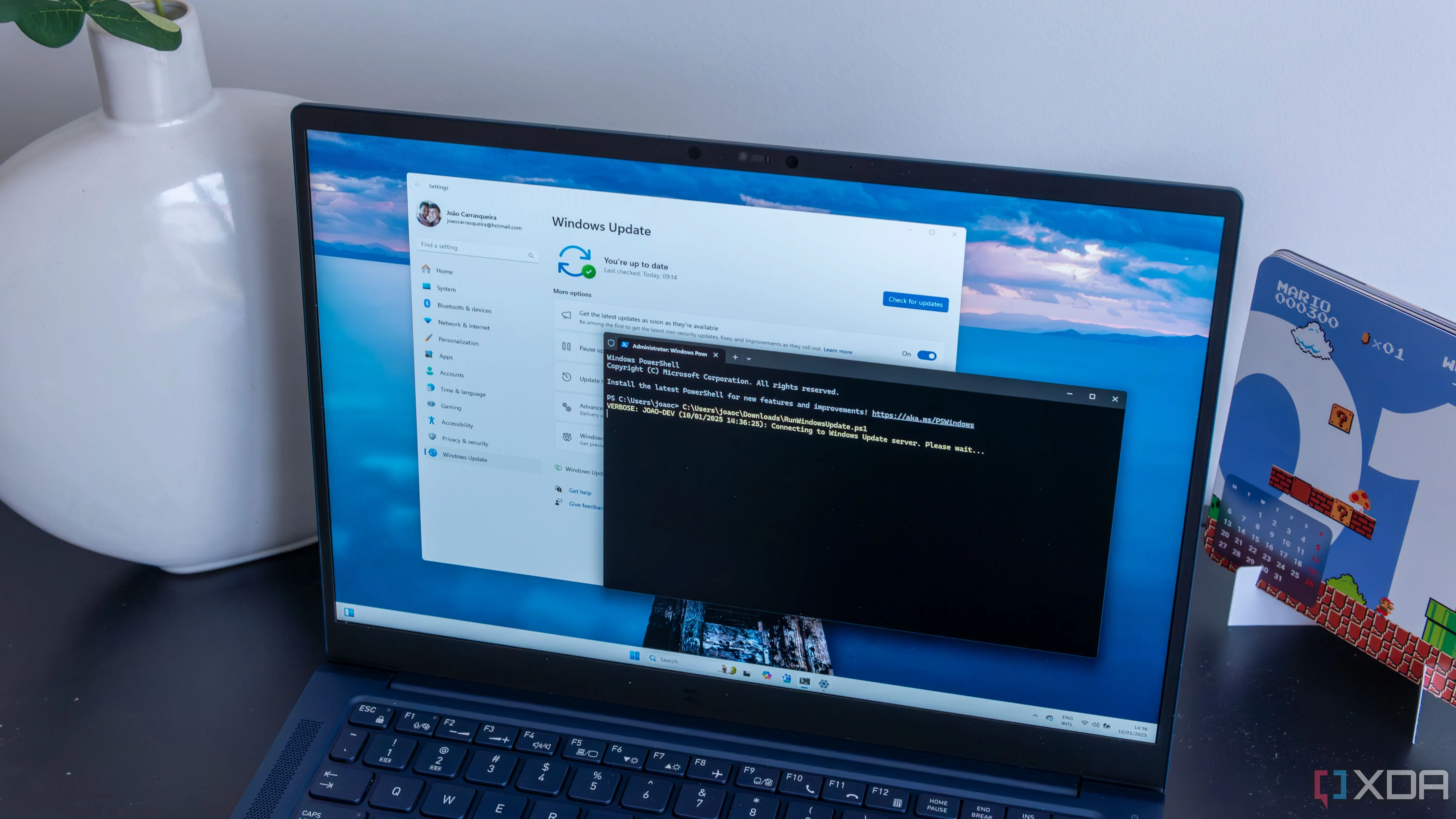 Máy tính xách tay chạy Windows 11 với cửa sổ PowerShell đang cài đặt các bản cập nhật, thể hiện tính kế thừa từ mô hình cập nhật của Windows 10