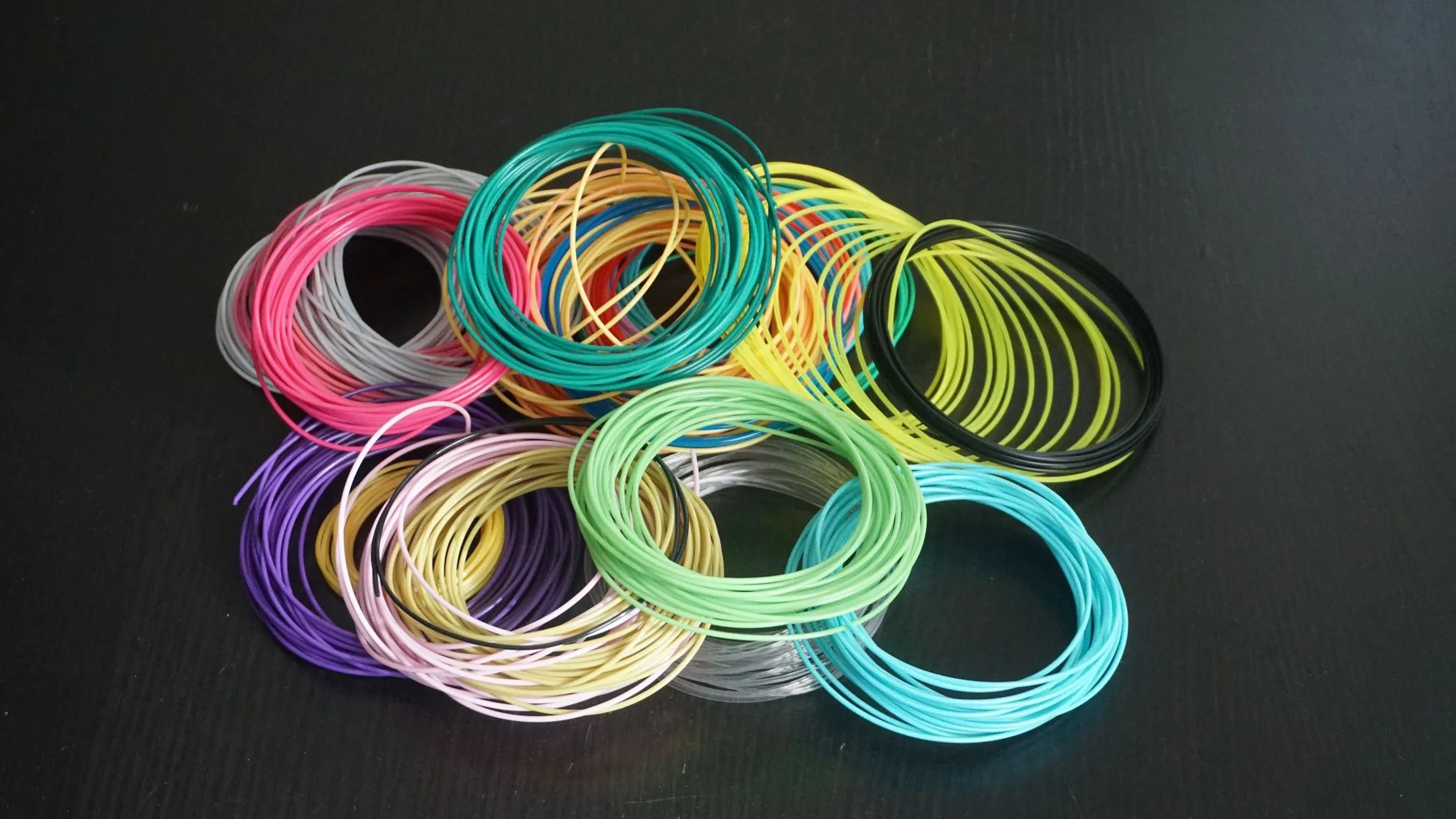 Các cuộn dây filament in 3D với nhiều màu sắc khác nhau, tượng trưng cho sự đa dạng vật liệu