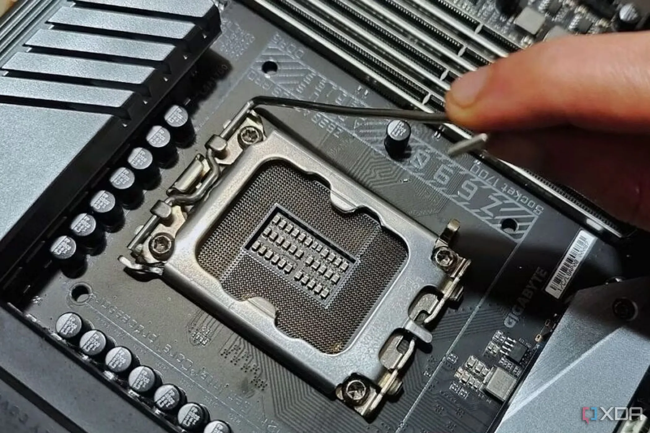 Cận cảnh socket CPU trên bo mạch chủ, với người đang giữ cần gạt kim loại