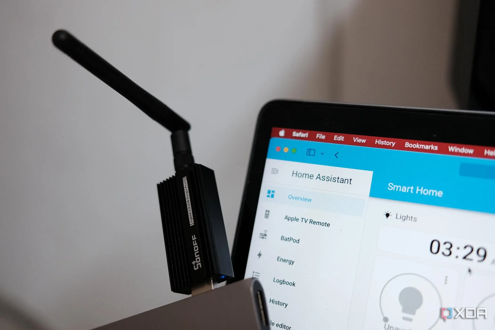 Đầu dongle Sonoff Zigbee trên bàn làm việc, trước màn hình MacBook hiển thị giao diện Home Assistant, minh họa tích hợp thiết bị cũ