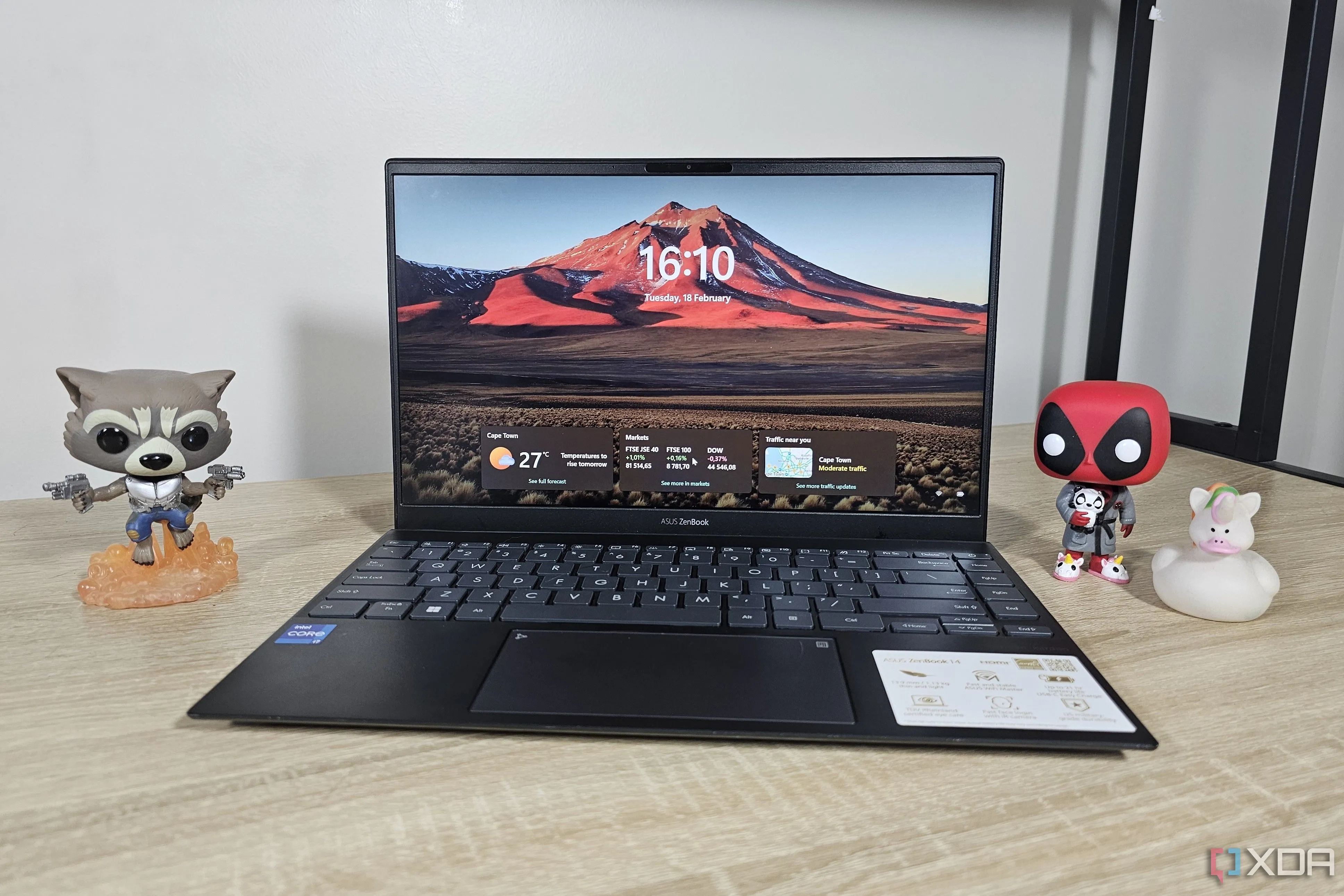 Laptop chạy Windows 11 đặt trên bàn làm việc cùng với các nhân vật nhỏ, thể hiện không gian làm việc hoặc giải trí