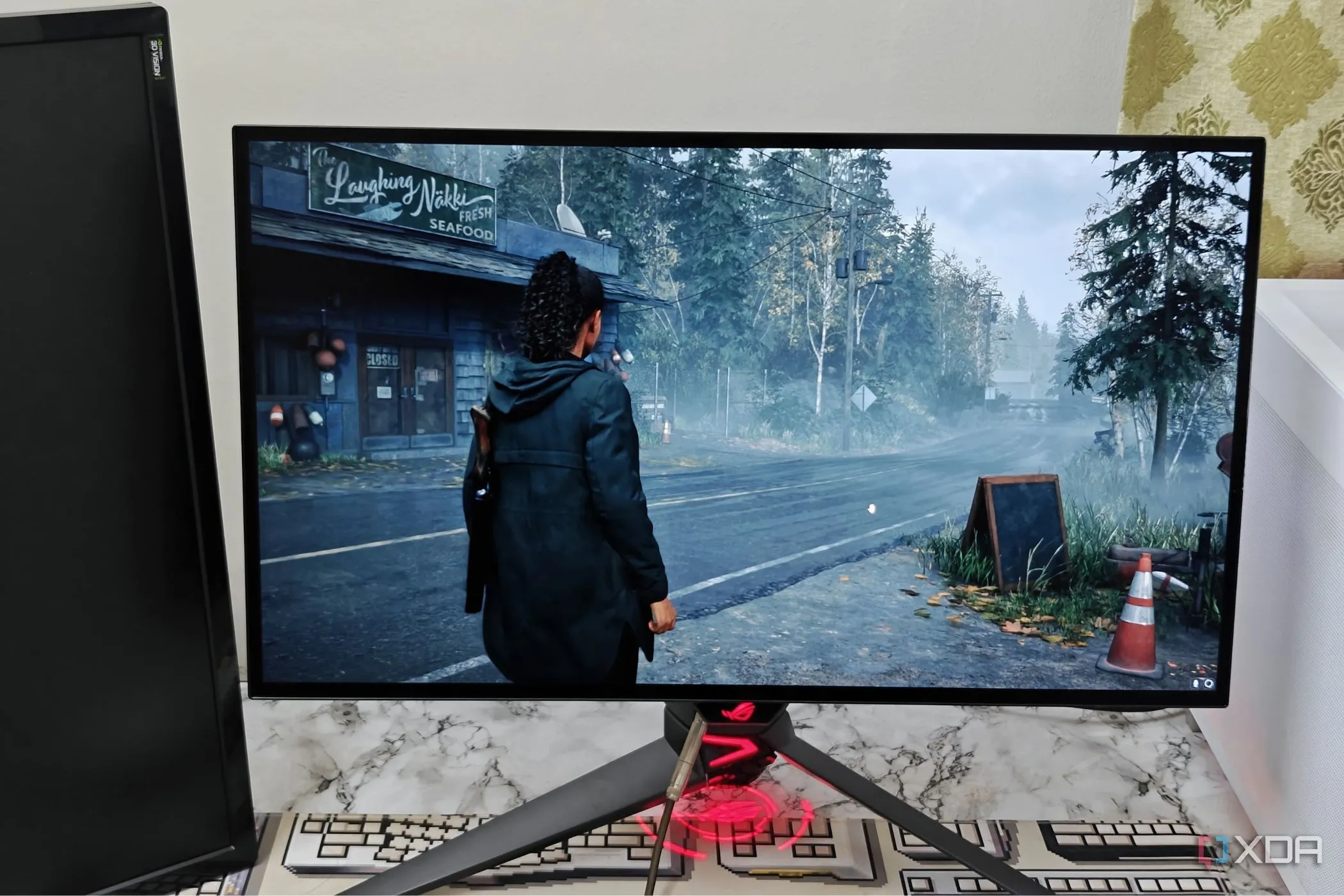 Màn hình gaming Asus ROG PG27AQDM hiển thị cảnh game Alan Wake 2 với đồ họa Ray Tracing ấn tượng, thể hiện sức mạnh của PC.