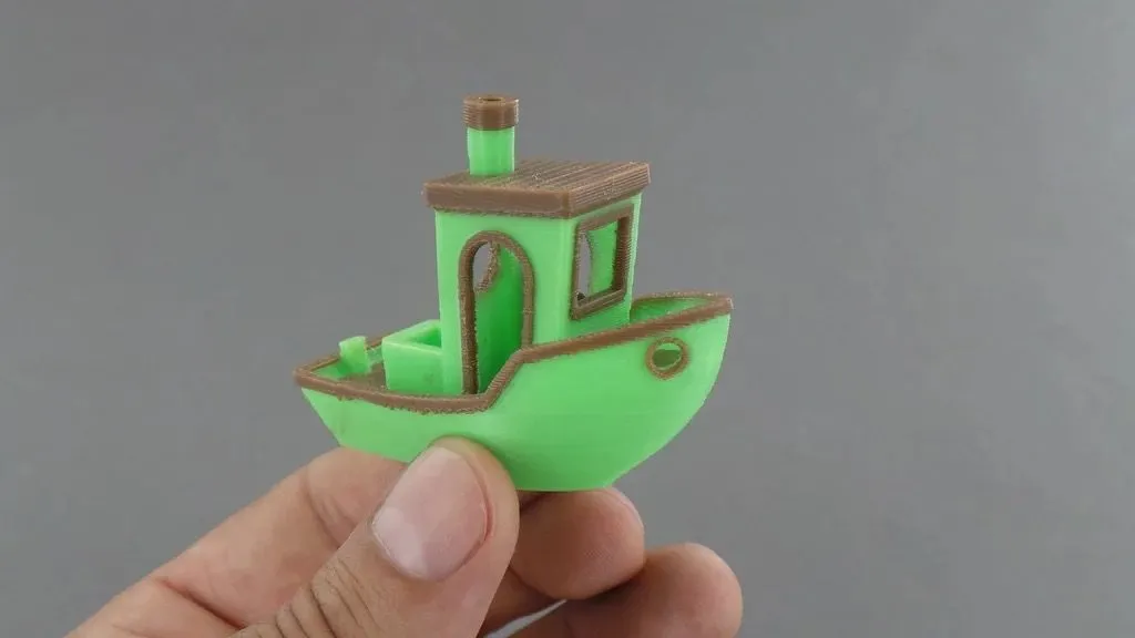Mô hình 3DBenchy in nhiều màu, tách rời từng phần, minh họa các vết Z-scars và đường nối lớp in cần cải thiện bề mặt.