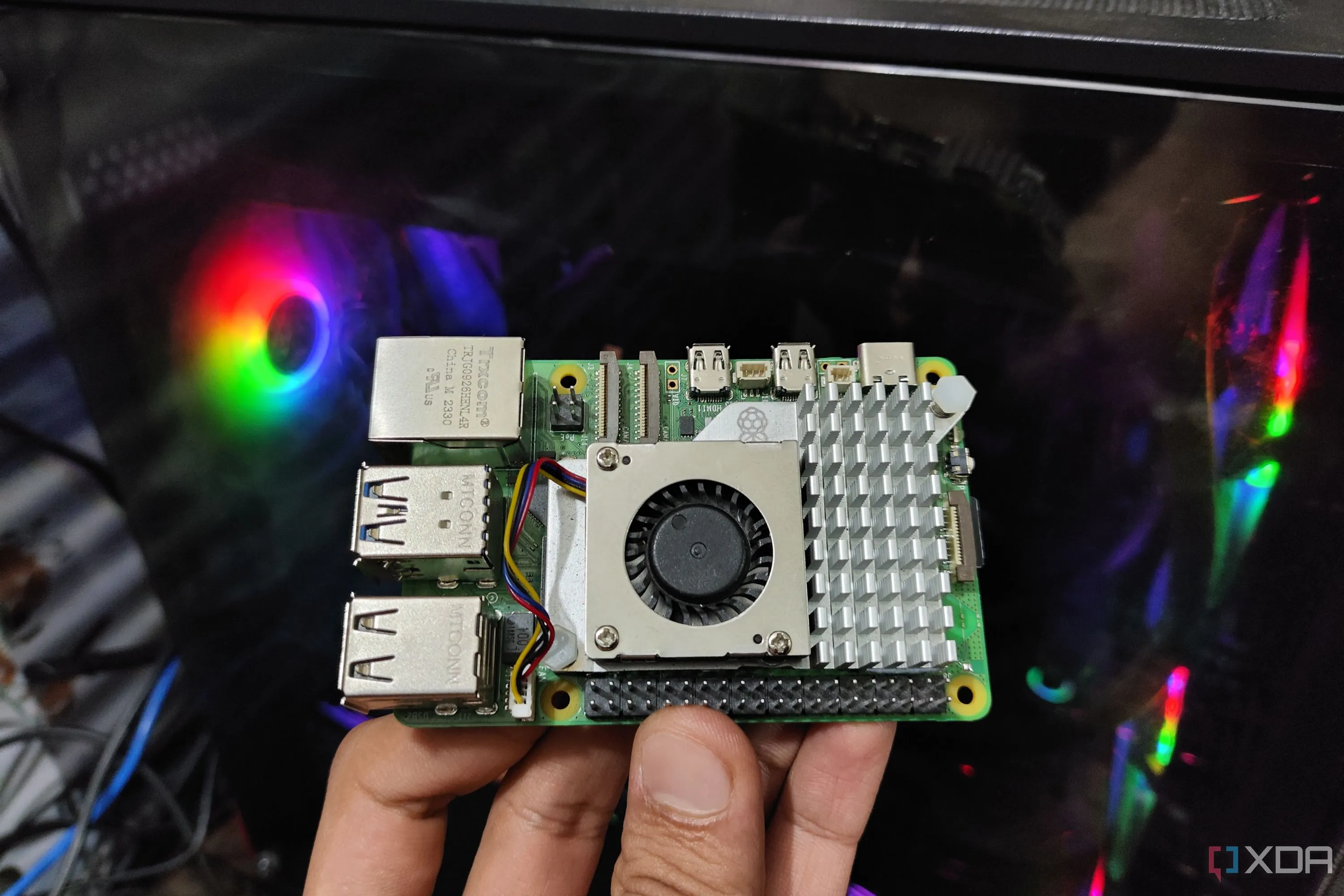 Một chiếc Raspberry Pi 5 được giữ trước màn hình máy tính, biểu trưng cho việc sử dụng phần cứng nhỏ gọn để tự host các dịch vụ văn phòng và đám mây cá nhân.