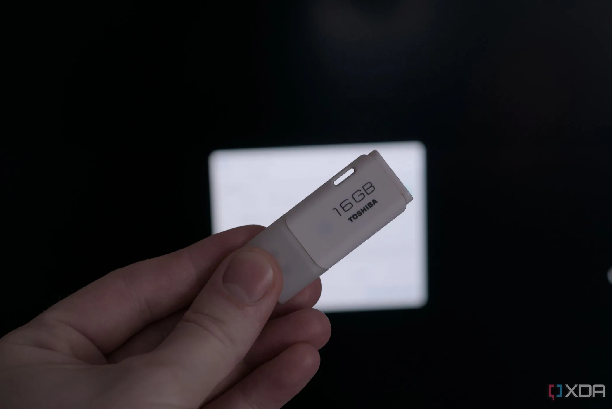 Một chiếc USB được cầm trên tay, biểu tượng cho nguy cơ từ thiết bị lưu trữ di động độc hại