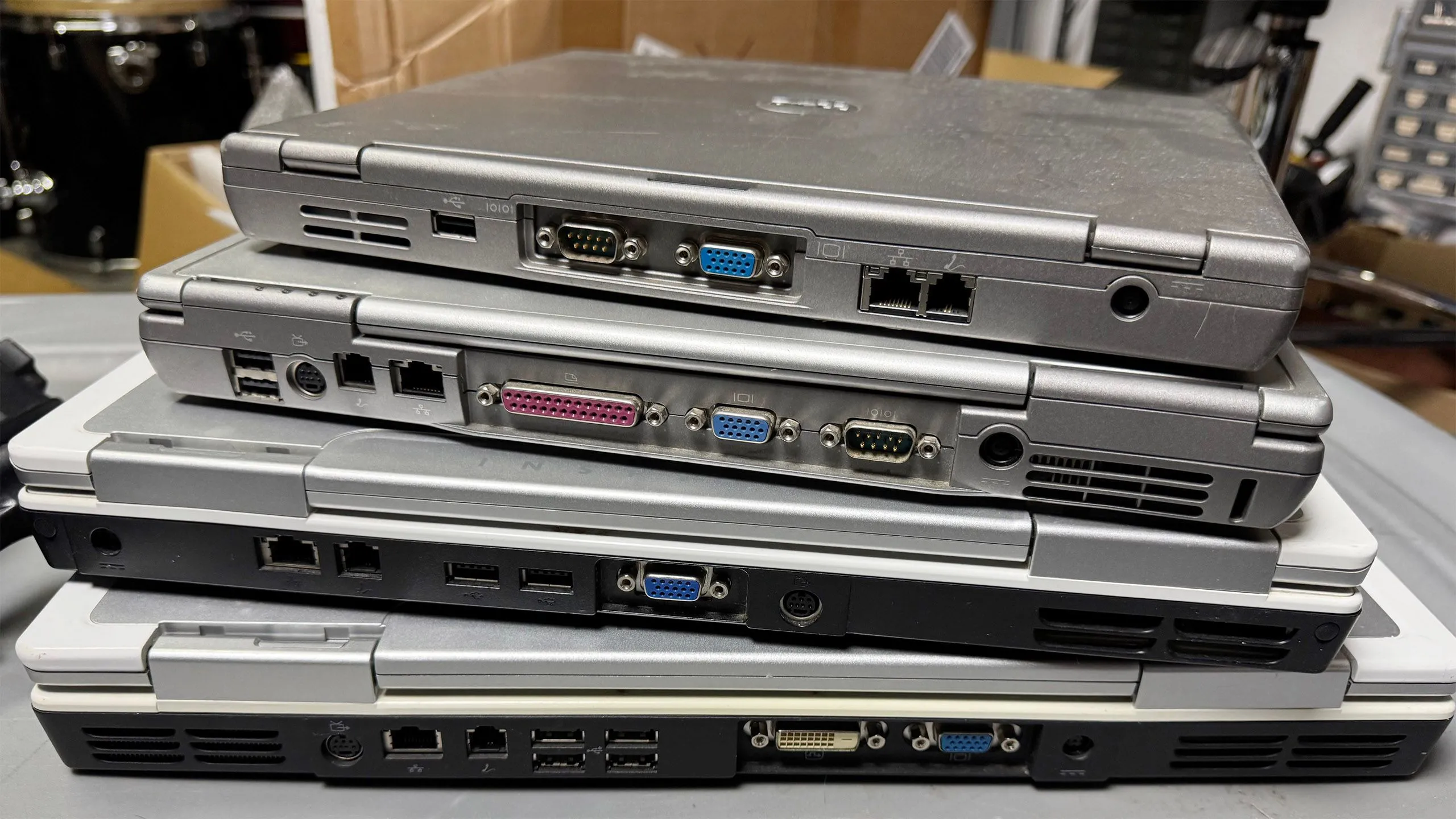 Một chồng laptop cũ với nhiều cổng kết nối, gợi ý về việc tái chế thiết bị cho home lab hoặc retro computing