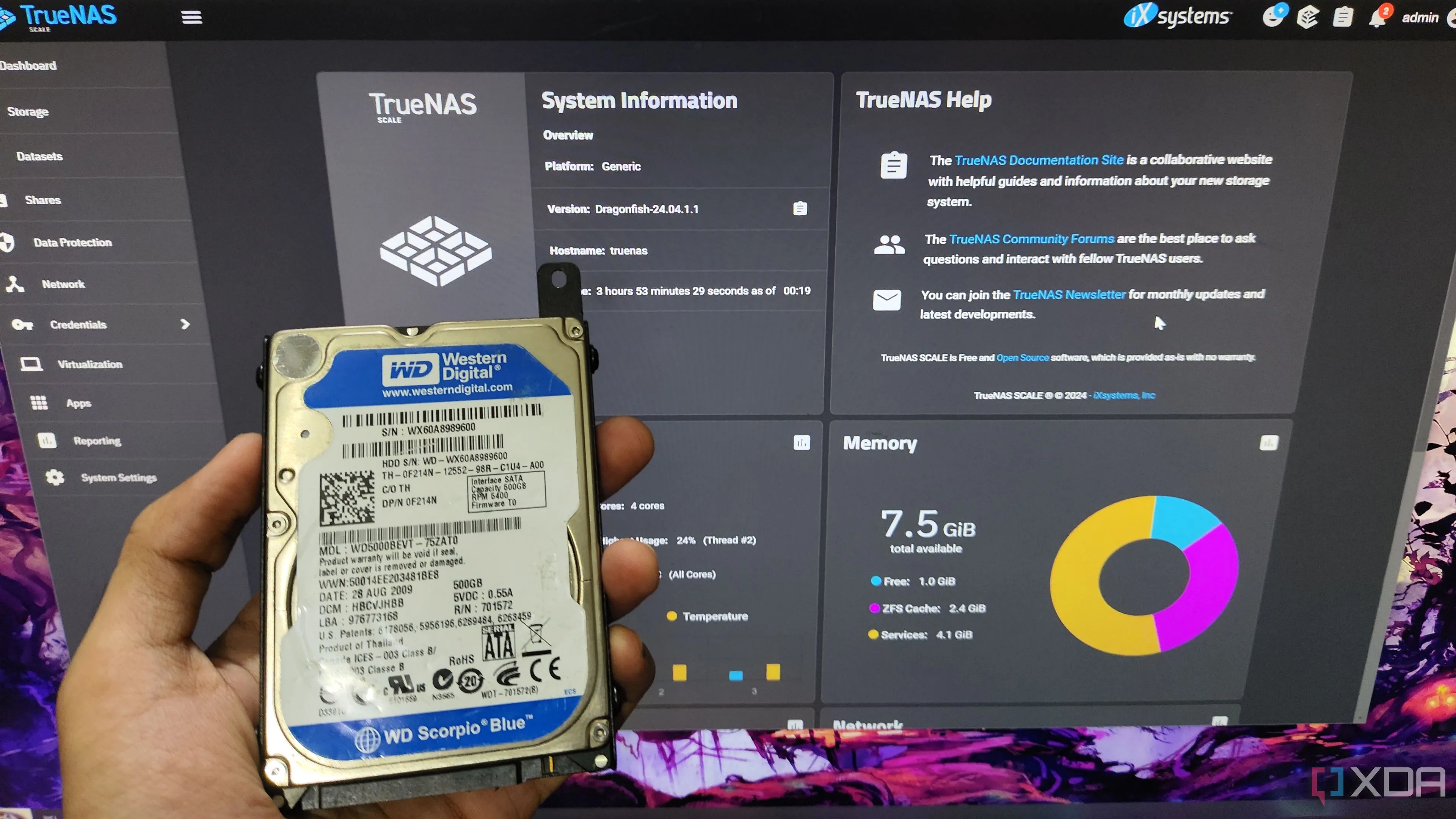 Một người đang cầm ổ cứng HDD trước màn hình hiển thị giao diện TrueNAS Scale, minh họa cho việc quản lý hệ thống NAS