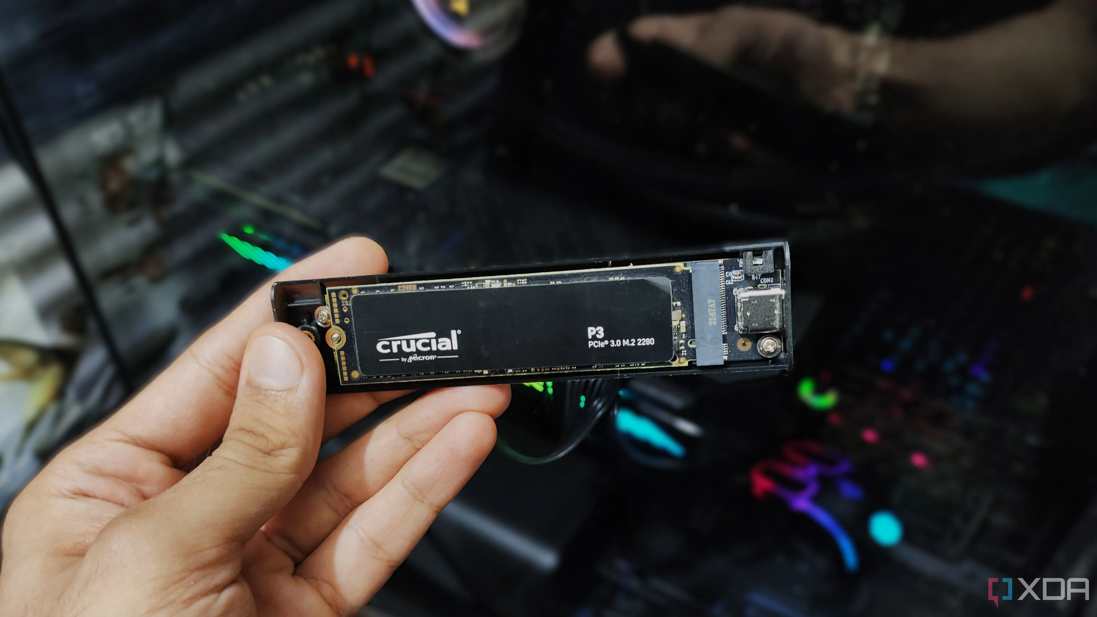 Một người đang cầm vỏ bảo vệ ổ cứng NVMe SSD, biểu thị tầm quan trọng của việc chọn ổ cứng tốc độ cao và dung lượng lớn cho PC gaming.
