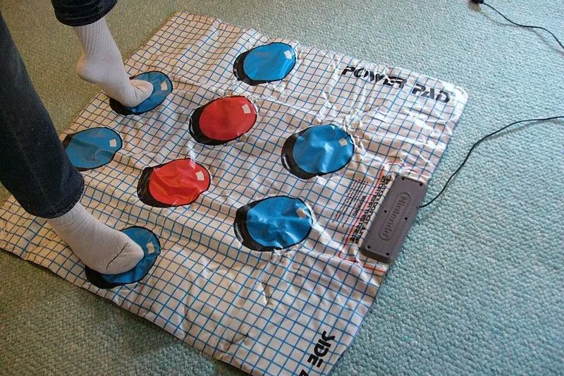 Một người đang đứng trên thảm điều khiển NES Power Pad để chơi game
