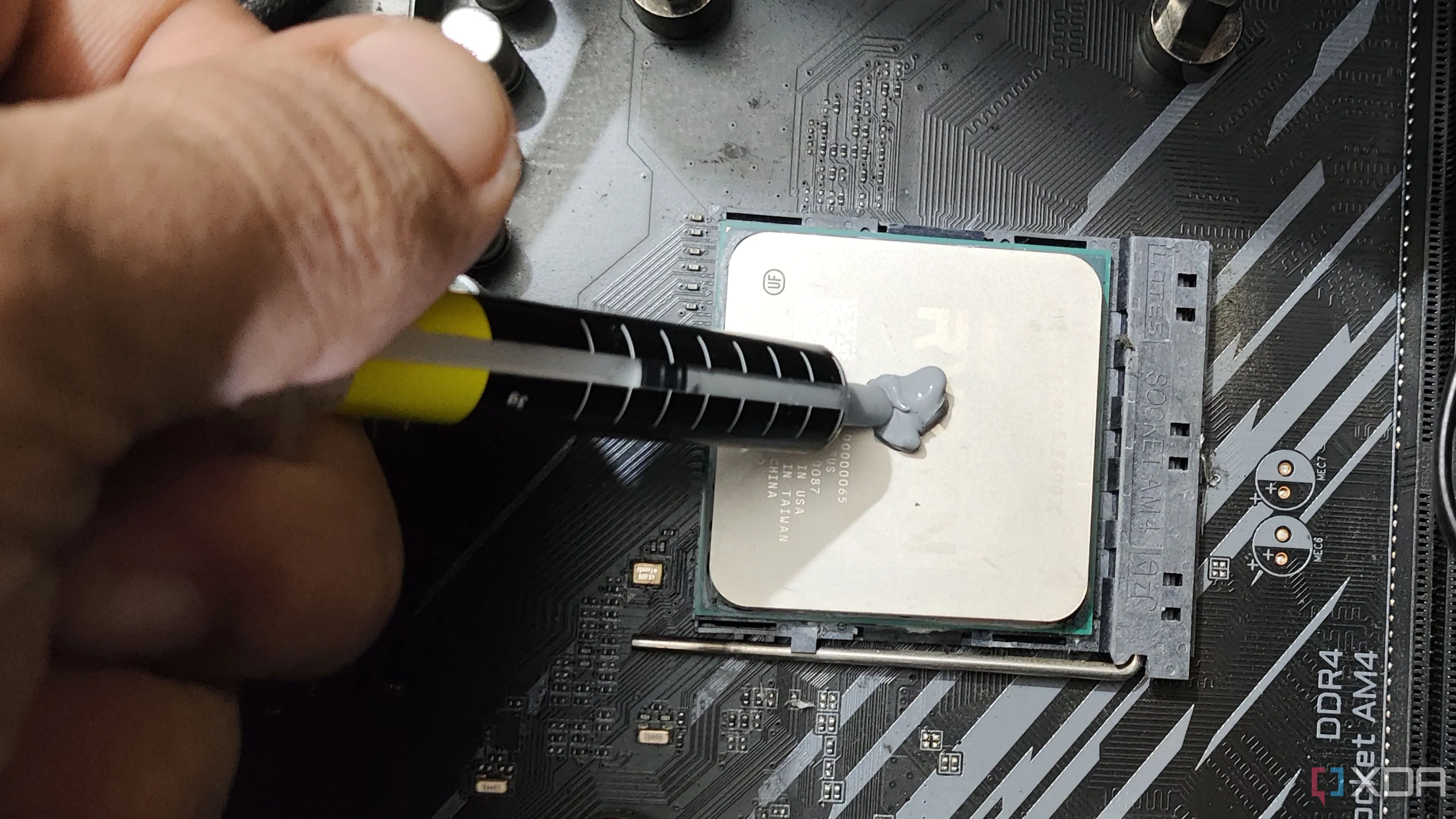 Một người đang thoa keo tản nhiệt lên CPU Ryzen 5 5600X, quy trình quan trọng để đảm bảo tản nhiệt hiệu quả.