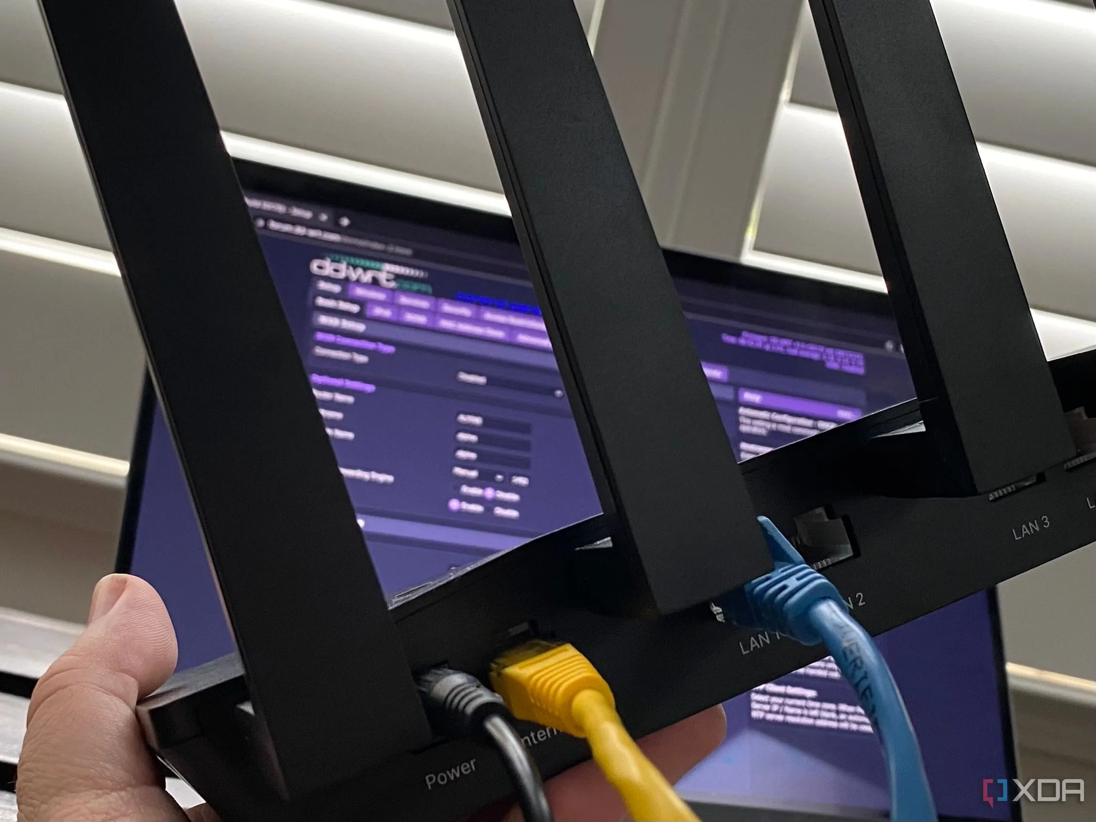 Một router Wi-Fi kết nối với laptop hiển thị giao diện phần mềm DD-WRT, minh họa việc sử dụng firmware tùy chỉnh để tăng cường bảo mật router