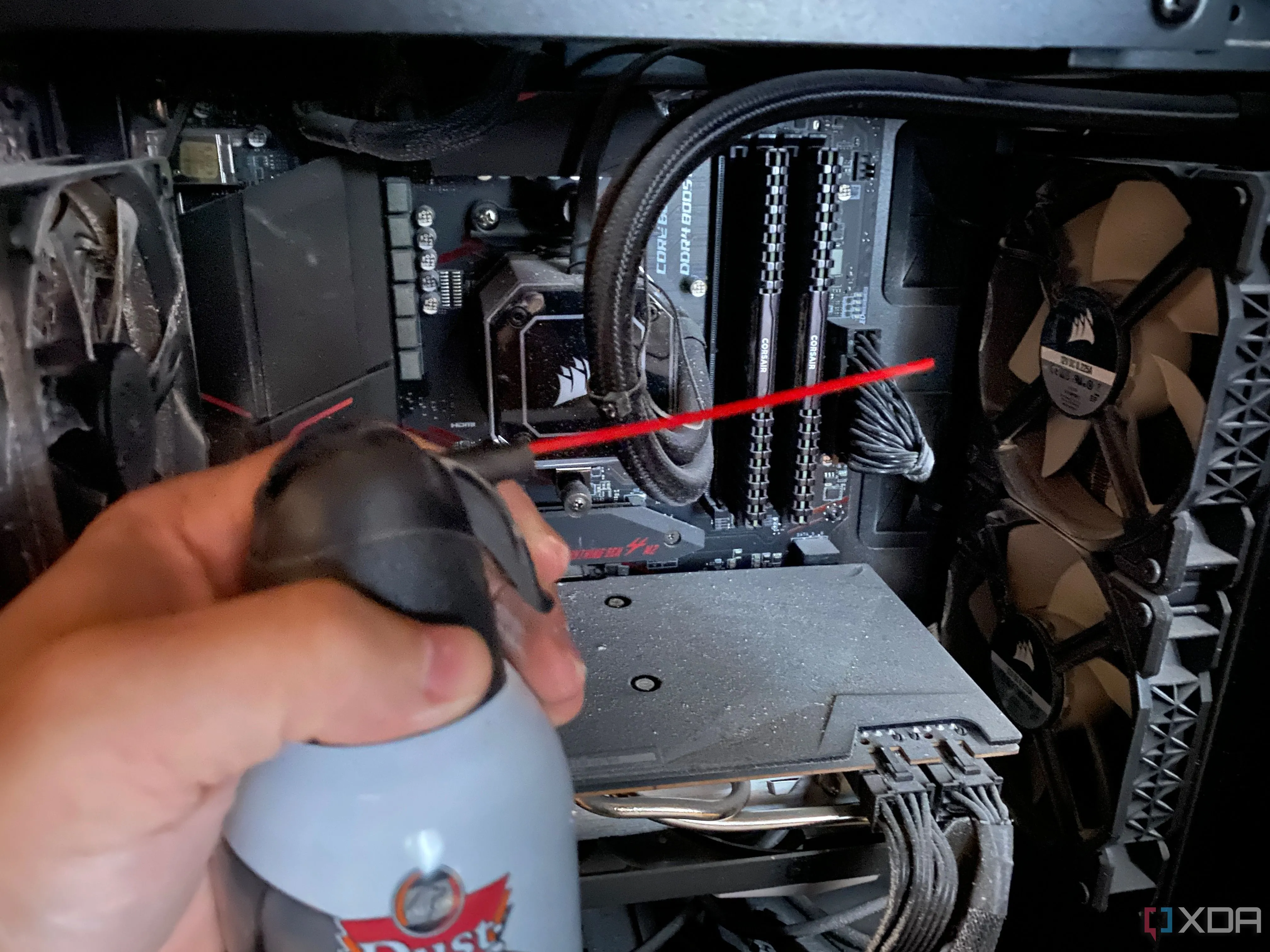 Người dùng đang dùng bình khí nén để thổi bụi ra khỏi vỏ case PC gaming, giúp cải thiện luồng khí và tản nhiệt.