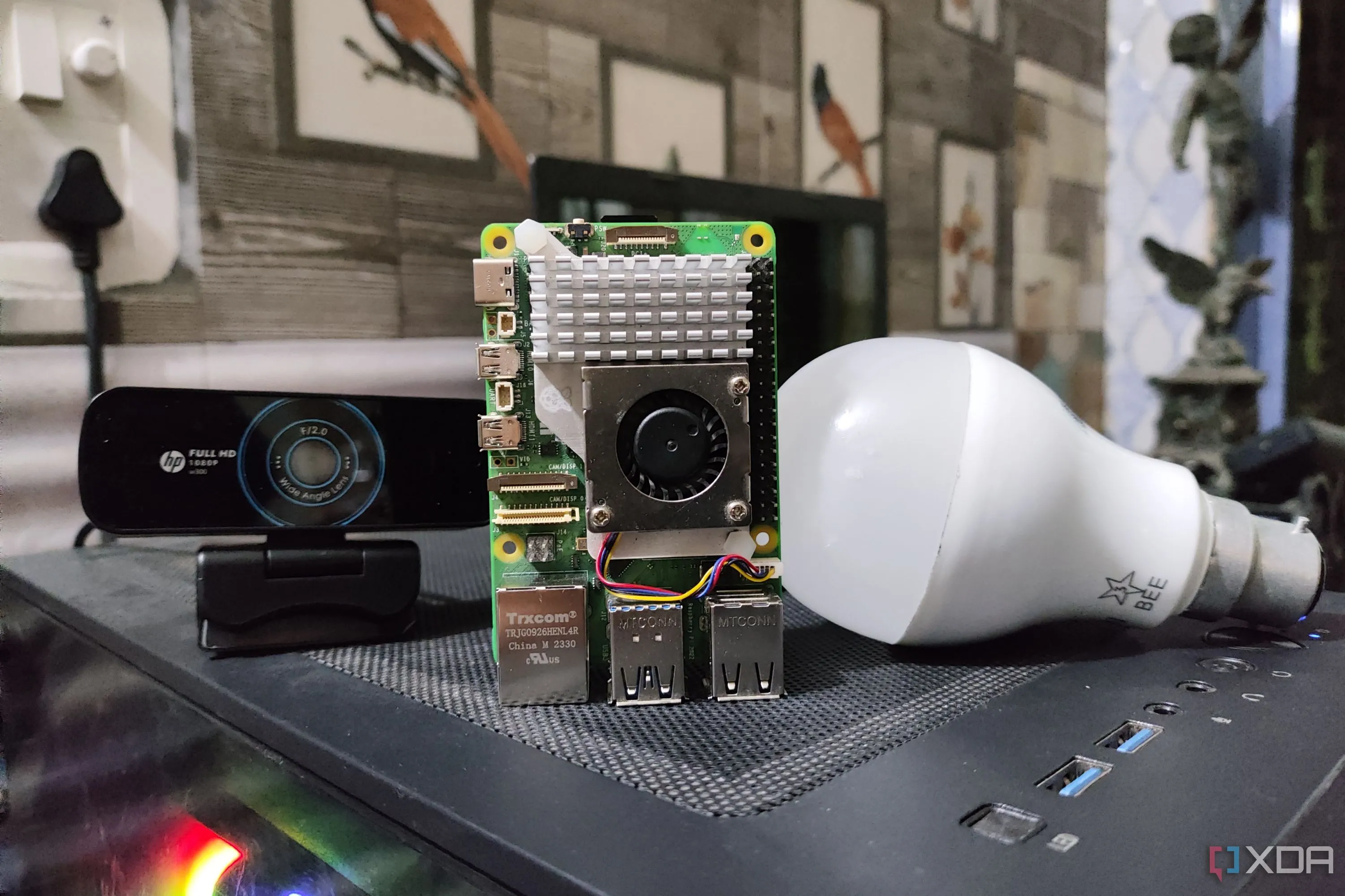 Raspberry Pi 5 đặt cạnh một webcam và một bóng đèn thông minh, thể hiện ứng dụng cho các dự án nhà thông minh tự làm