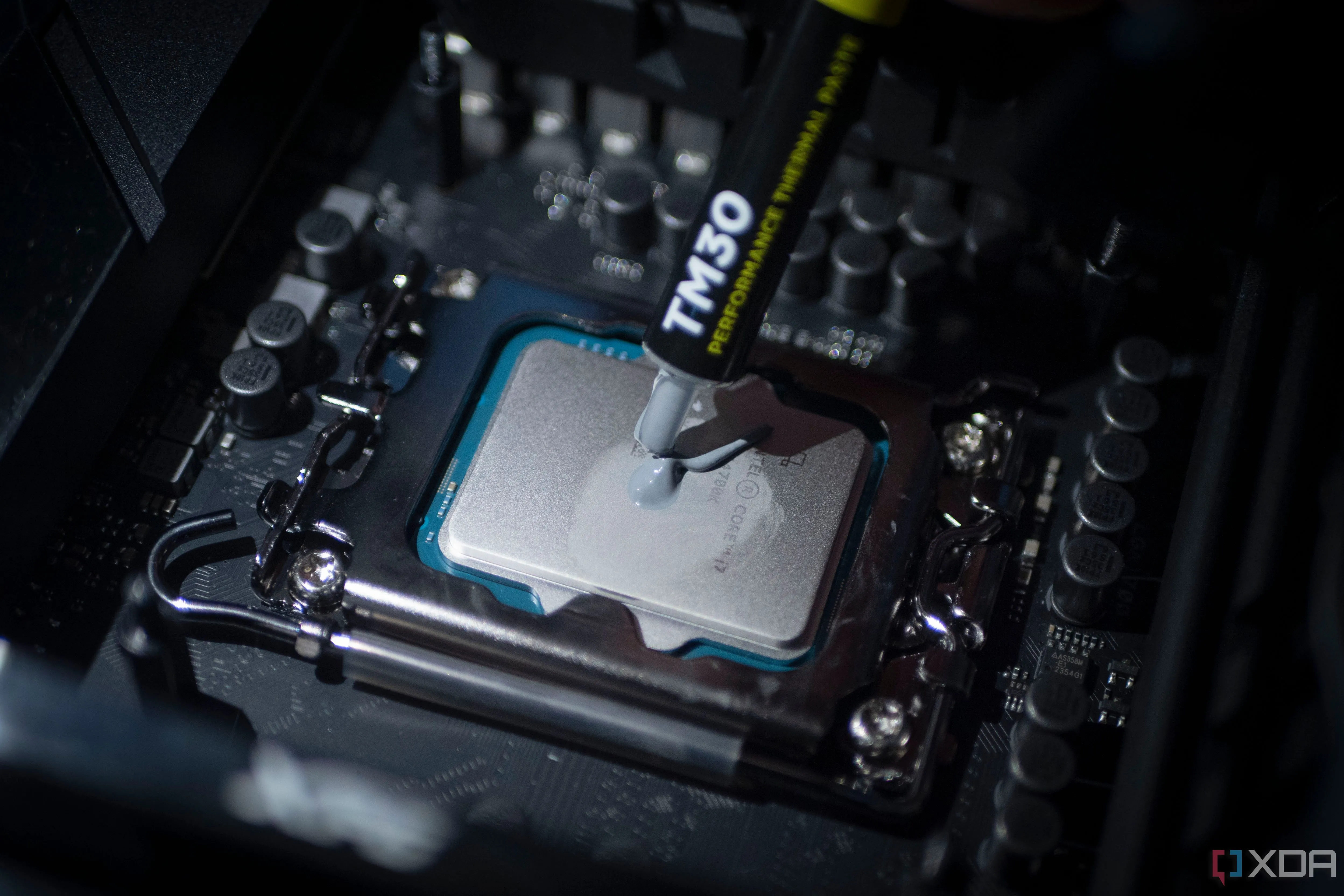 Thợ kỹ thuật đang thoa keo tản nhiệt lên CPU Intel Core i7-14700K, một bước quan trọng khi lắp đặt hoặc nâng cấp CPU để đảm bảo hiệu suất