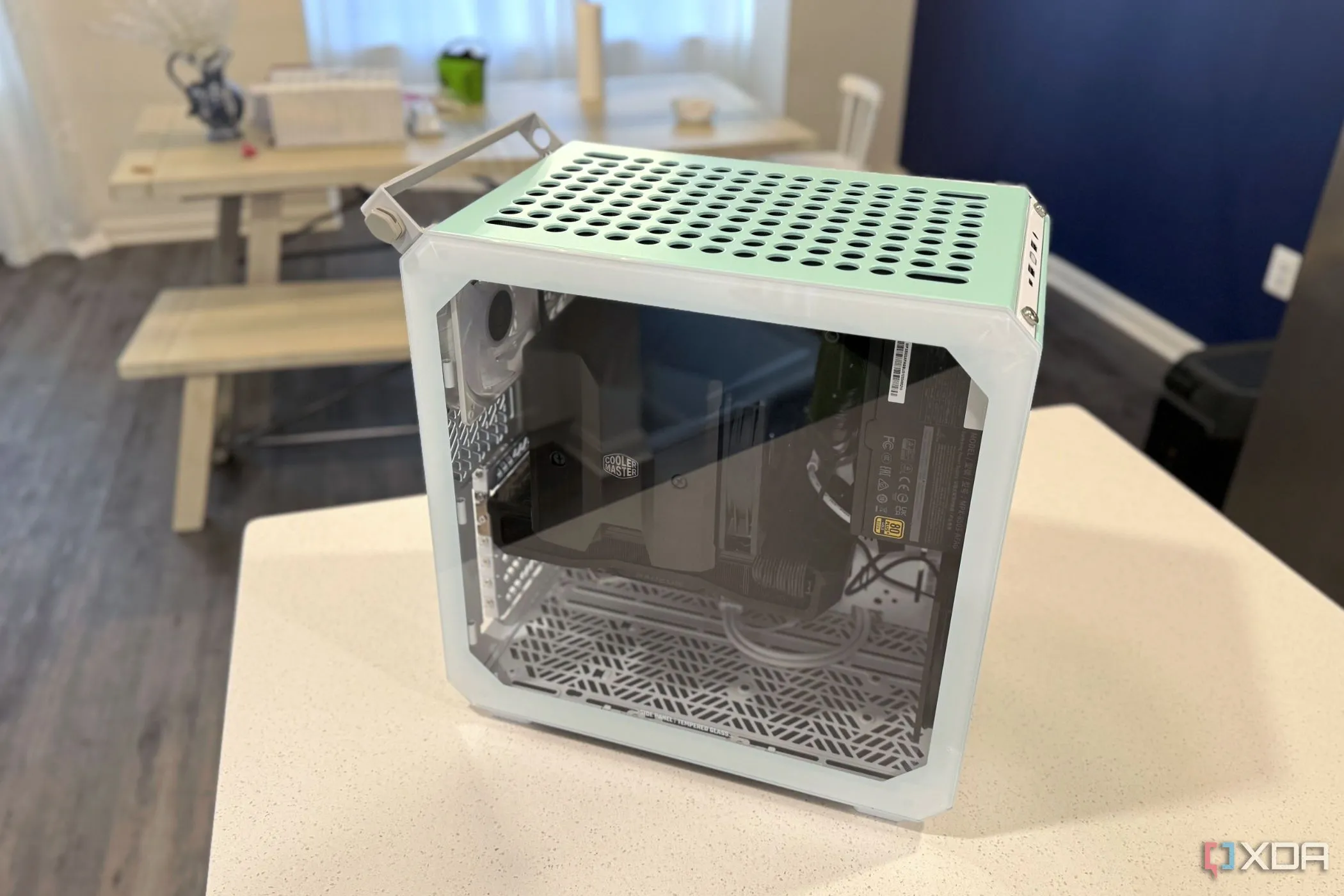 Vỏ case Cooler Master Qube 500 được đặt trên bàn bếp, cho thấy kích thước nhỏ gọn nhưng cũng ngụ ý khả năng tản nhiệt hạn chế